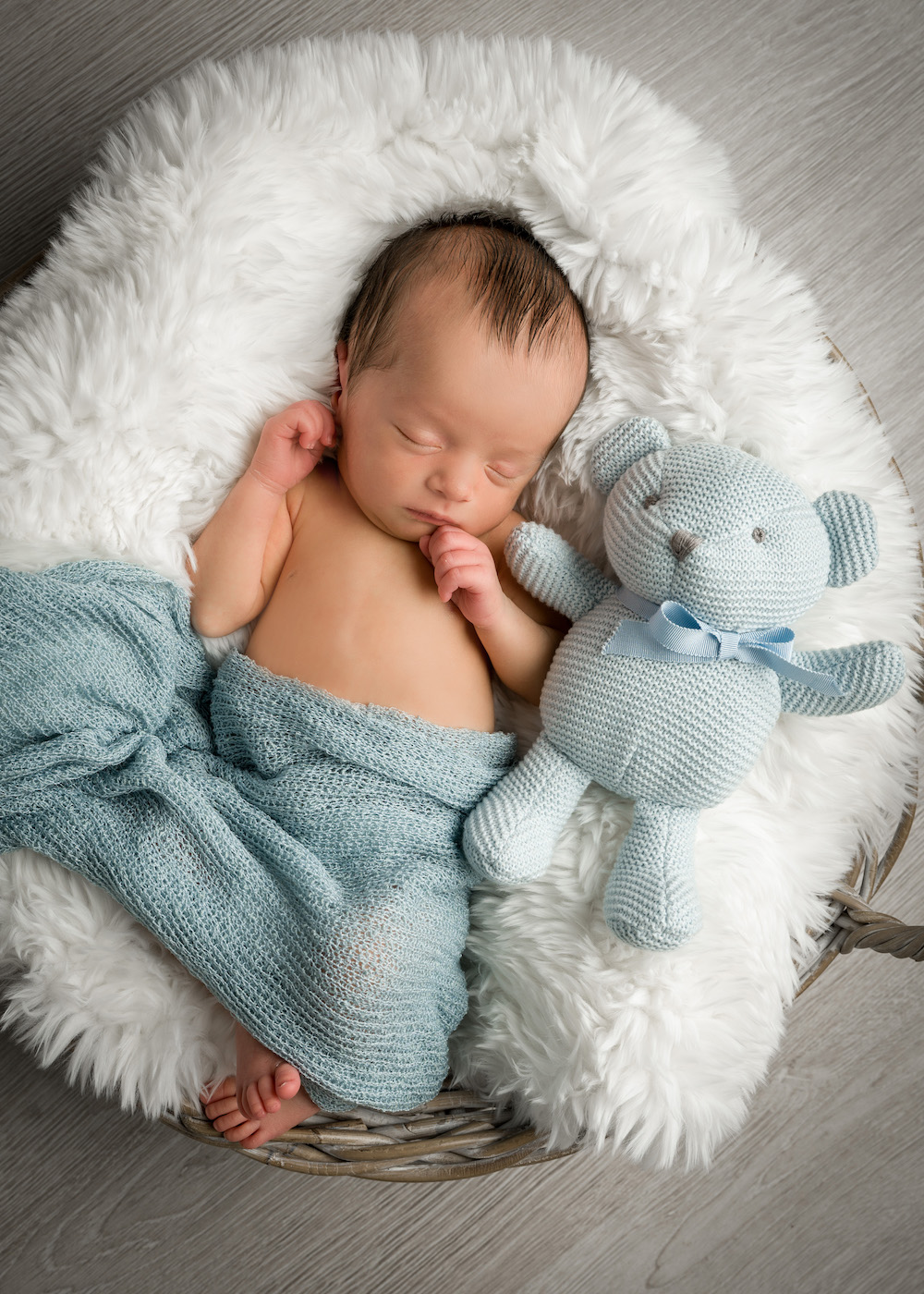 Baby schlafend im Korb mit Kuscheltier